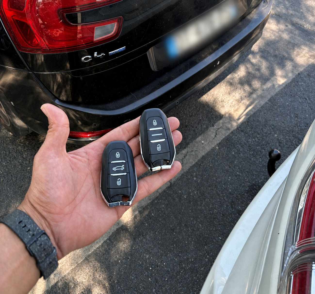 Deux clés automobiles présentées devant un véhicule, plaque d’immatriculation anonymisée